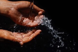 hands cupping water on a black background