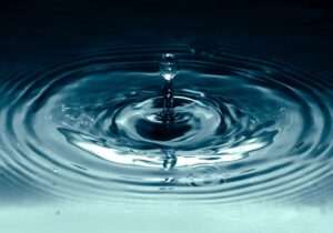 Water droplet into dark blue water pool
