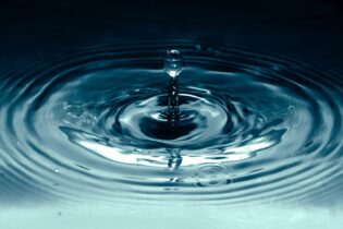 Water droplet into dark blue water pool