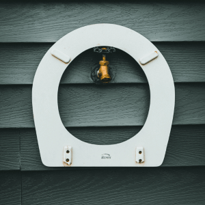 Water faucet in a wall surrounded by a toilet seat