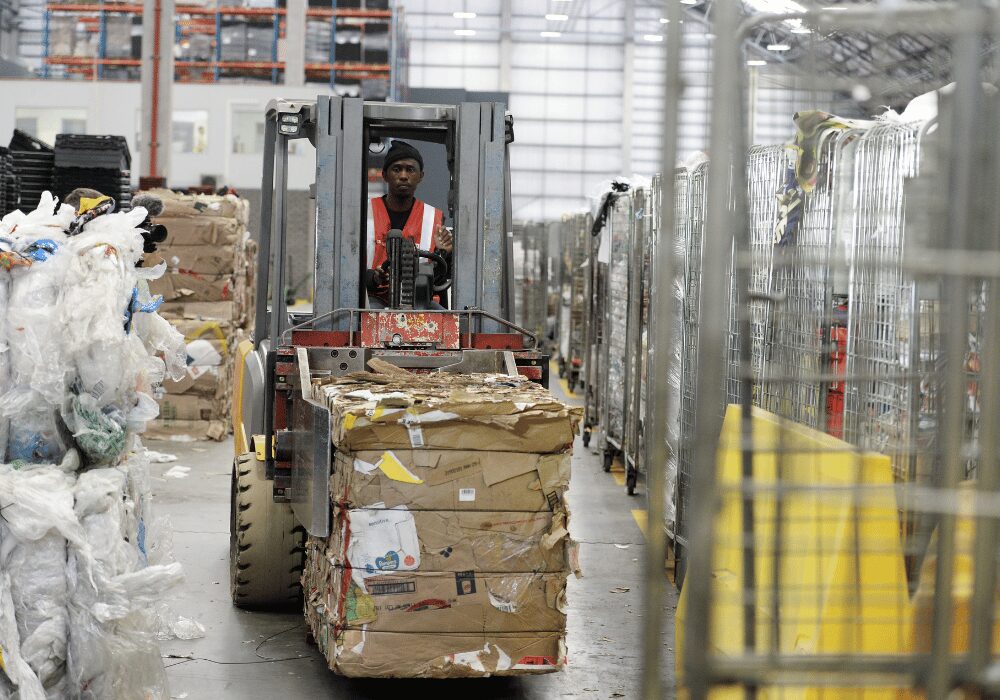 Shoprite worker transporting recycled packed cardboard within warehouse