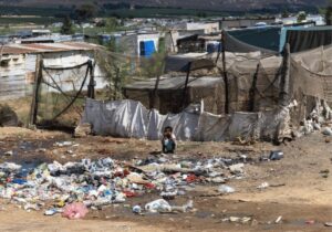 A child squats in front of a rubbish heap in Riverview, Citrusdal.