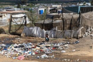 A child squats in front of a rubbish heap in Riverview, Citrusdal.