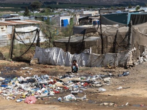 A child squats in front of a rubbish heap in Riverview, Citrusdal.