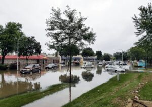 Flooded street with cars next to store