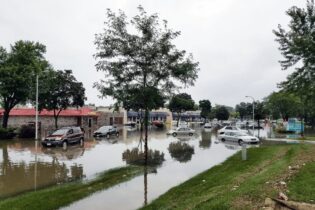 Flooded street with cars next to store