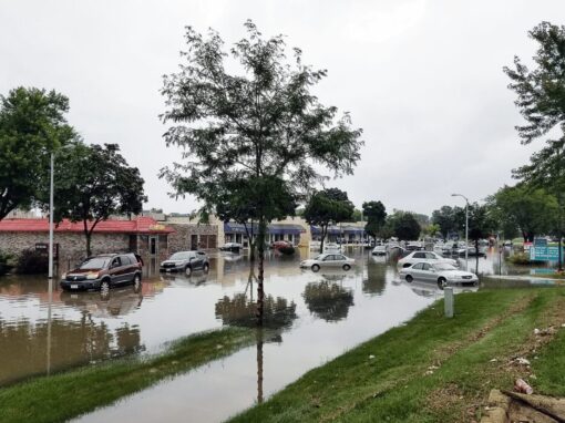 Flooded street with cars next to store