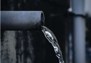clean water running out of a water pipe of a dark background