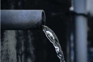 clean water running out of a water pipe of a dark background