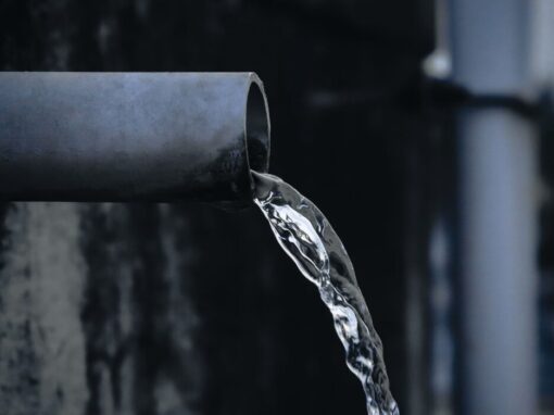 clean water running out of a water pipe of a dark background