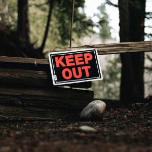 keep out sign across wooden post fence