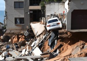 An urban four-storey building where the bottom storey and a parking lot have been washed away by floods