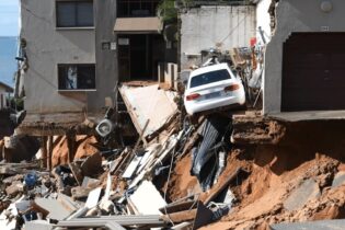 An urban four-storey building where the bottom storey and a parking lot have been washed away by floods
