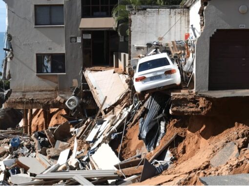 An urban four-storey building where the bottom storey and a parking lot have been washed away by floods