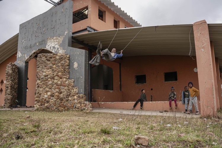 Children play on a makeshift swing in the remains of a library in Letsopa, damaged during protests against the Tswaing Local Municipality in 2019.