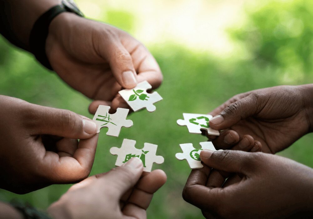 four people with green recycling puzzle pieces