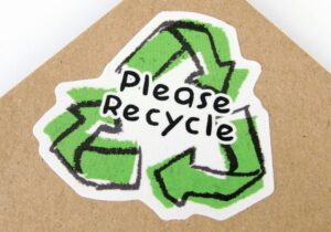 please recycle green sign over a cardboard sheet