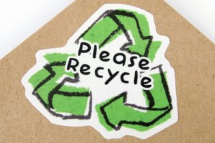 please recycle green sign over a cardboard sheet
