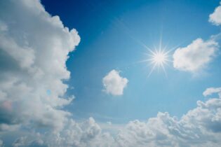 sun in a blue sky surrounded by clouds