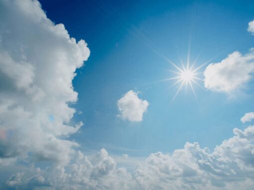 sun in a blue sky surrounded by clouds
