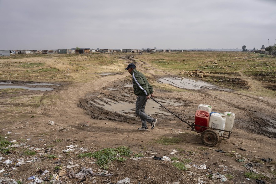 Johannes Montsho, 66, pulls a trolley filled with water buckets to his home in Agisanang.