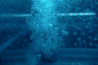 water bubbles beneath the surface in a blue toned image