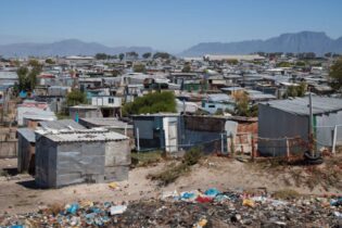 Corrugated metal shacks and a littered open space in an informal settlement