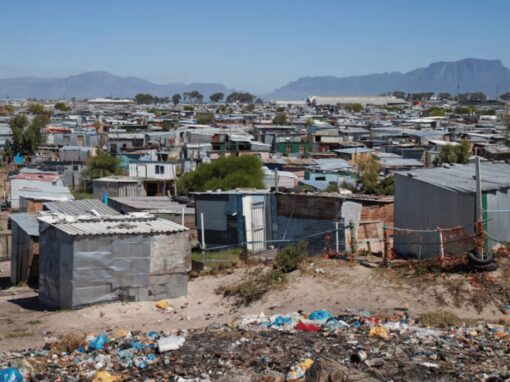 Corrugated metal shacks and a littered open space in an informal settlement