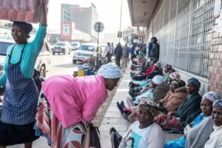 Elderly women sit in a row on a city pavement