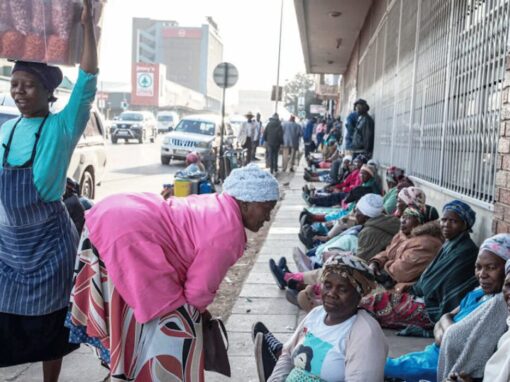 Elderly women sit in a row on a city pavement