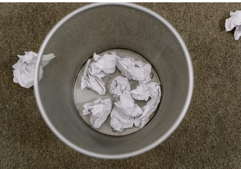 balls of paper rolled up into a trash can