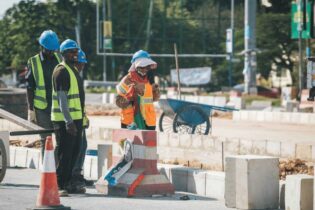 construction workers cementing in concrete blocks on road side