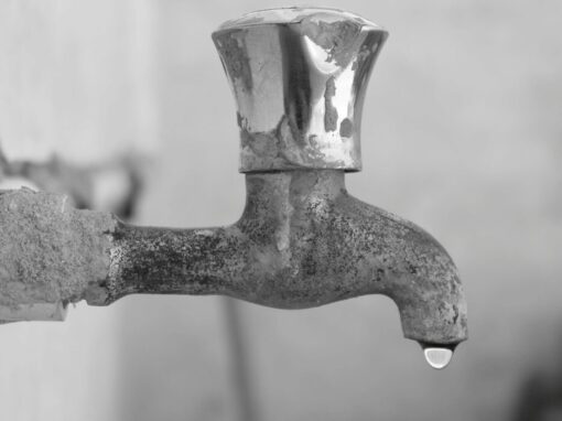 leaking tap with a droplet of water in greyscale
