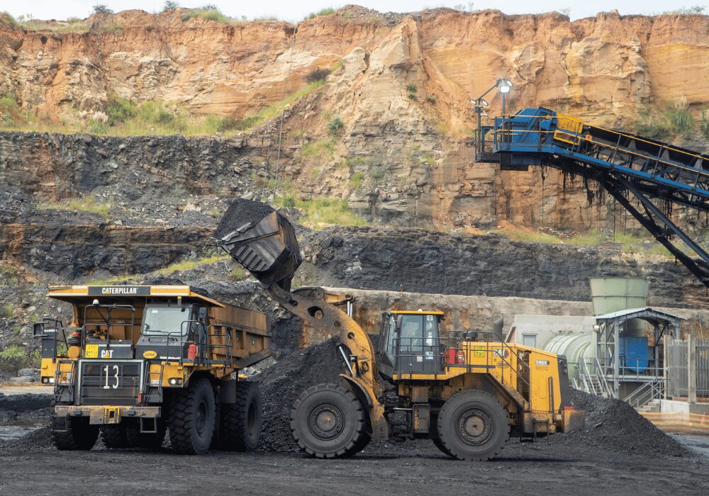 mining vehicles infront of a deep excavation site