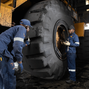 two civil engineers beside a large construction truck tyre